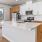 Studios In Boise, ID - The Timber at Harris Ranch - Gourmet Quartz Kitchen, Stainless Steel Appliances, Kitchen Island, Vinyl Plank Flooring, Sleek White & Hardwood Cabinets, And Floor to Ceiling Windows
